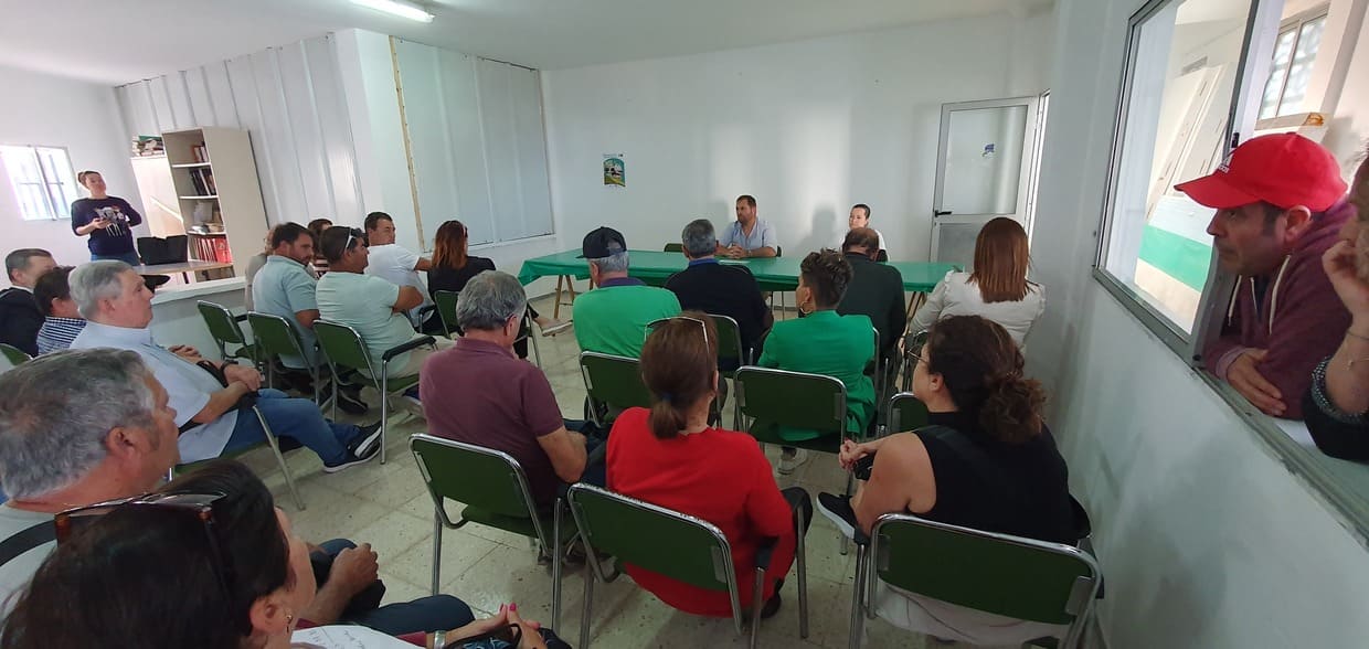 imagen de la reunión mostrando asistentes sentados y ponentes al fondo