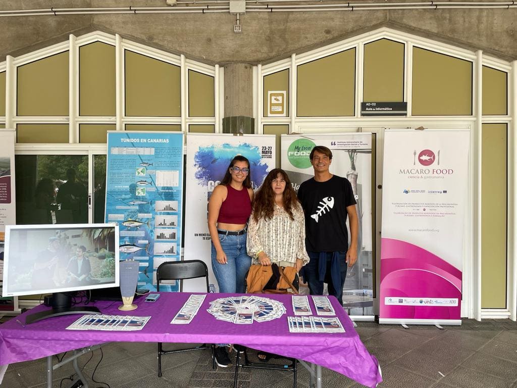 imagen de 2 alumnas y 1 alumno freten a cartel de proyecto